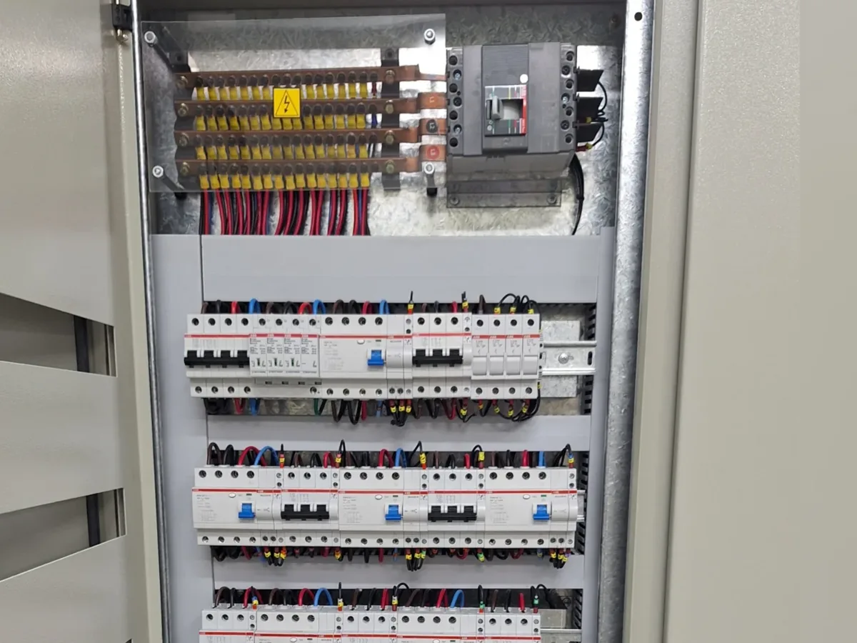Tablero general de potencia abierto: barras de cobre, interruptor principal y filas de térmicas y disyuntores cableados y rotulados