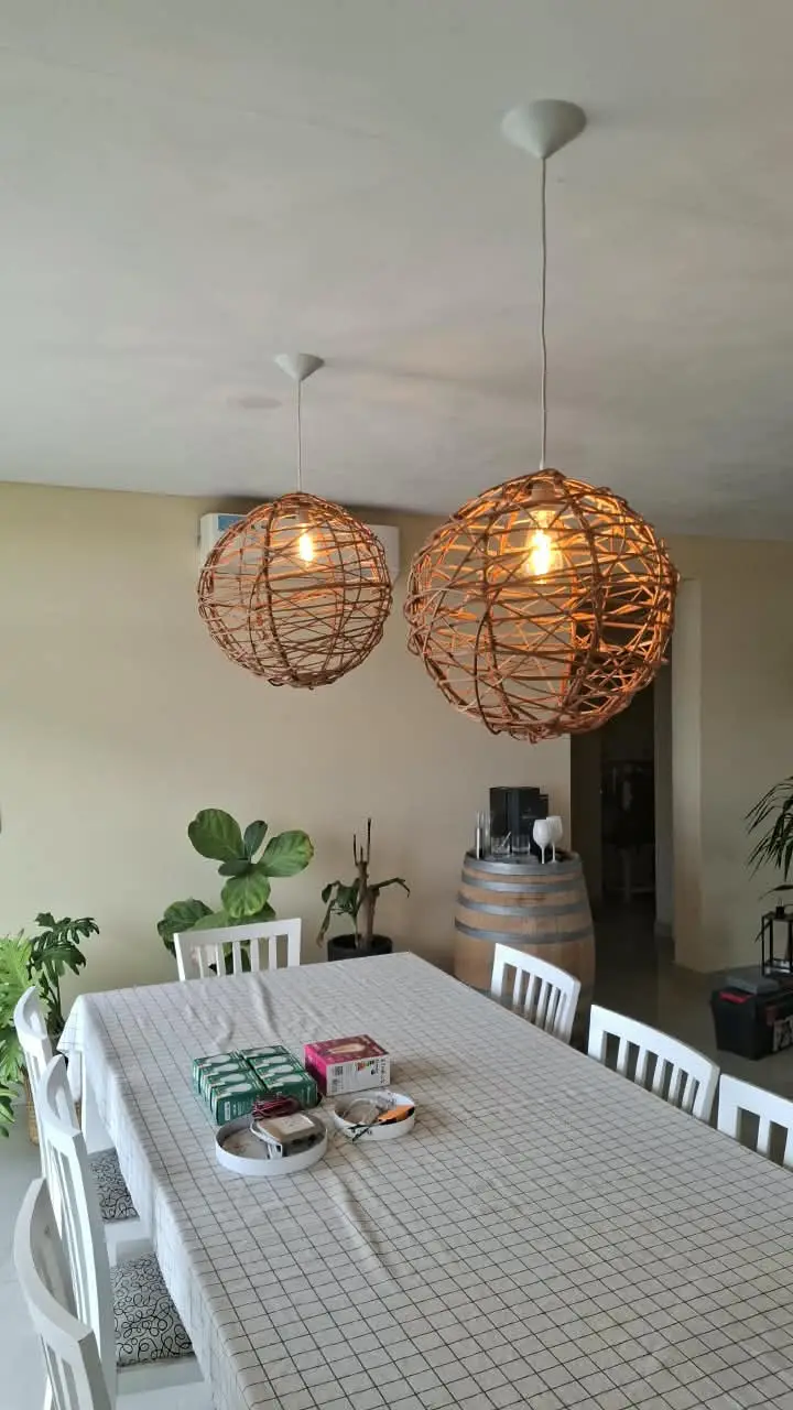 Comedor con las dos luminarias colgantes de mimbre encendidas
